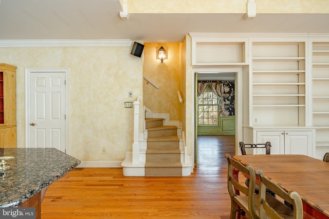 interior space featuring built in features, light hardwood / wood-style flooring, and crown molding