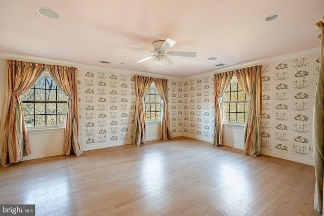 spare room with light wood-type flooring, plenty of natural light, ornamental molding, and ceiling fan