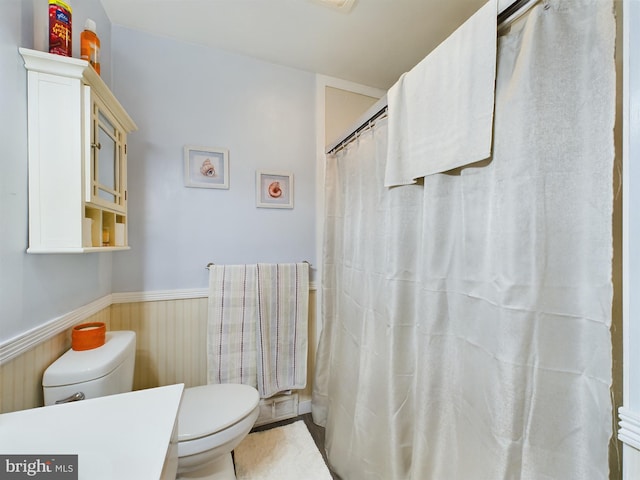 bathroom with radiator heating unit, curtained shower, vanity, and toilet