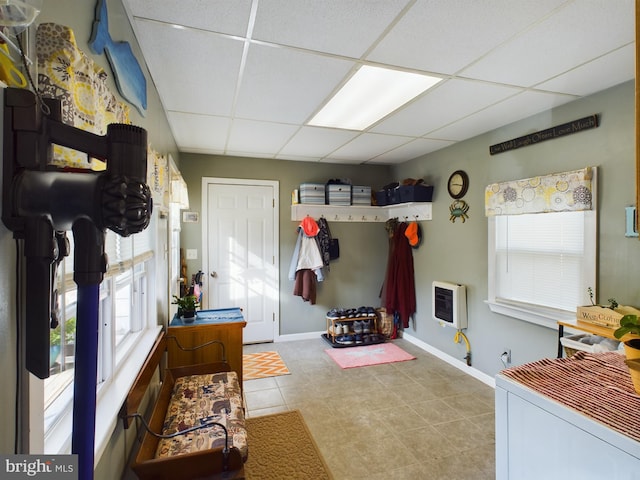 interior space with heating unit, a drop ceiling, and light tile patterned flooring