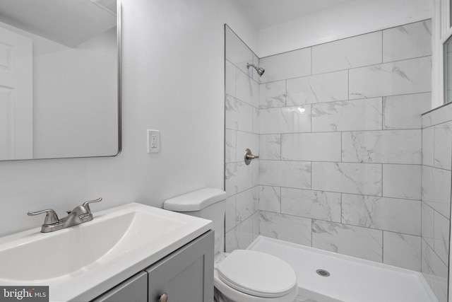 bathroom featuring vanity, toilet, and tiled shower