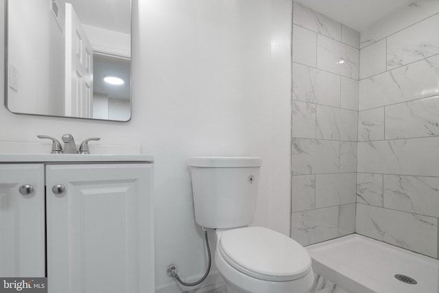 bathroom featuring tiled shower, toilet, and vanity