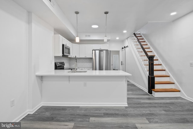 kitchen featuring stainless steel appliances, white cabinetry, sink, decorative light fixtures, and a barn door