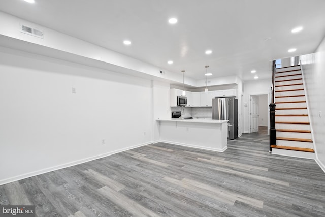 kitchen with stainless steel appliances, hardwood / wood-style flooring, white cabinetry, kitchen peninsula, and decorative light fixtures