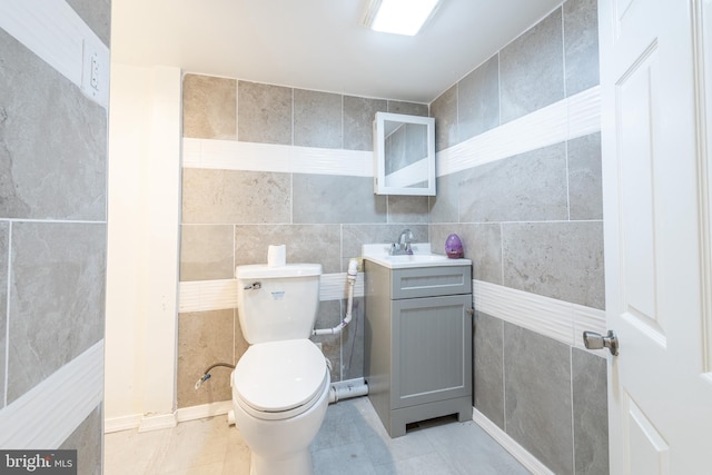 bathroom featuring vanity, toilet, tile patterned floors, and tile walls