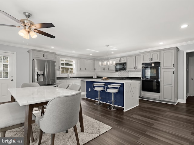 dining area with ornamental molding, sink, ceiling fan with notable chandelier, and dark hardwood / wood-style flooring