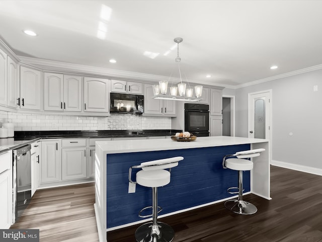 kitchen featuring wood-type flooring, a center island, black appliances, and decorative light fixtures