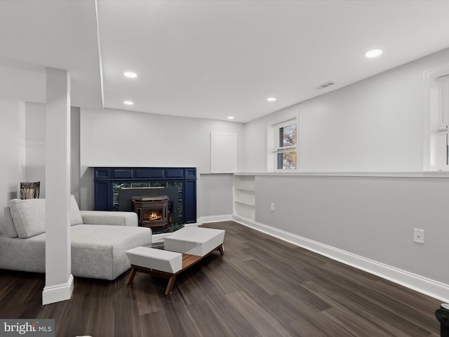 living room with dark wood-type flooring and a wood stove