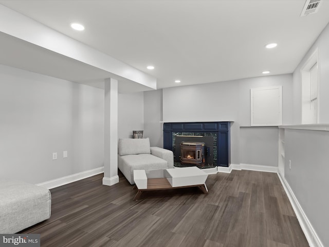 sitting room featuring a wood stove and dark hardwood / wood-style flooring