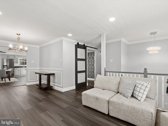 living room with crown molding, a barn door, a notable chandelier, and dark hardwood / wood-style flooring