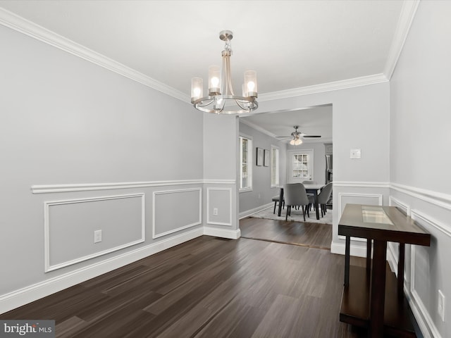 dining space featuring dark wood-type flooring, crown molding, and ceiling fan with notable chandelier