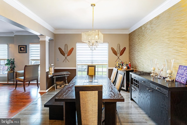 dining area with ornamental molding, a chandelier, decorative columns, and hardwood / wood-style floors