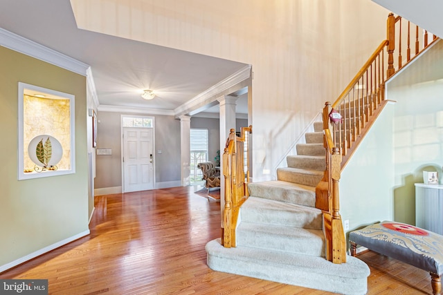 entryway featuring hardwood / wood-style flooring, crown molding, and ornate columns