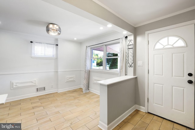 entryway with ornamental molding and light hardwood / wood-style flooring