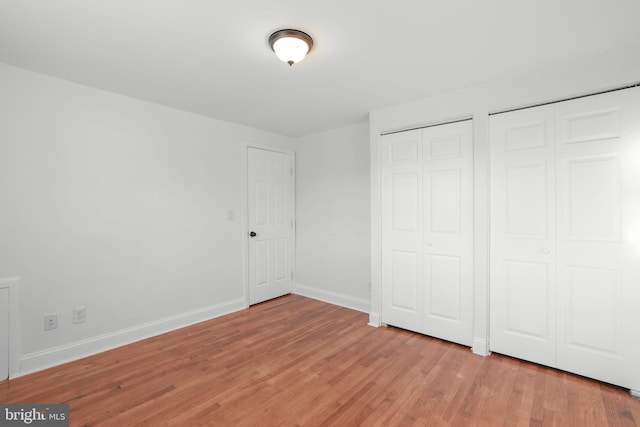 unfurnished bedroom featuring light hardwood / wood-style flooring and multiple closets