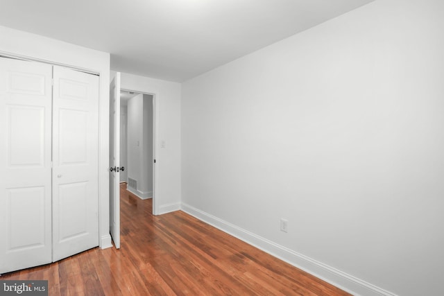 unfurnished bedroom featuring a closet and dark wood-type flooring