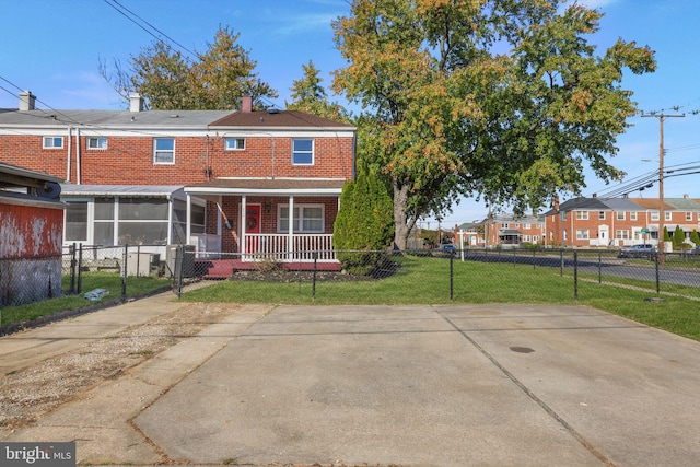 back of house with covered porch, a sunroom, and a lawn