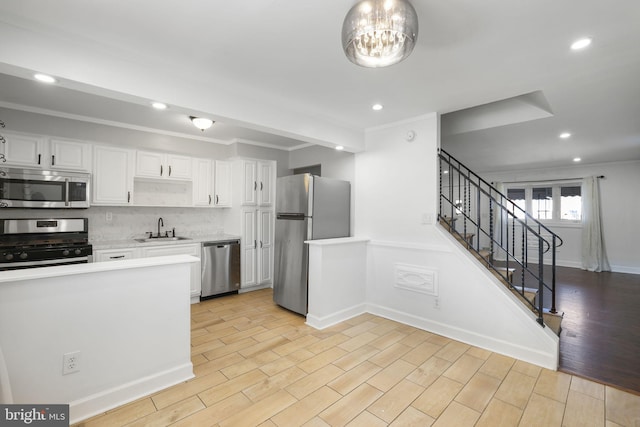 kitchen with sink, light wood-type flooring, white cabinetry, stainless steel appliances, and crown molding