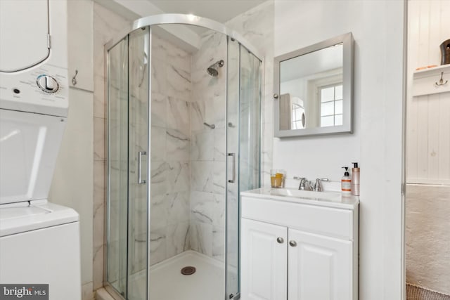 bathroom with vanity, a shower with door, and stacked washing maching and dryer