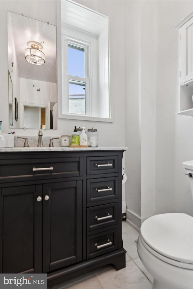 bathroom featuring a notable chandelier, vanity, and toilet