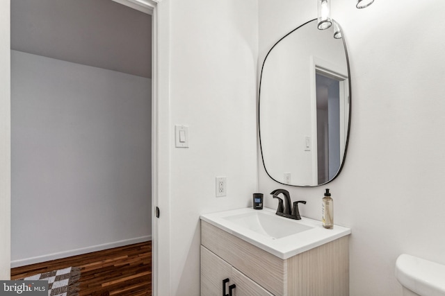 bathroom with vanity, toilet, and hardwood / wood-style flooring