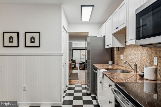 kitchen featuring decorative backsplash, white cabinets, stone countertops, stainless steel appliances, and sink