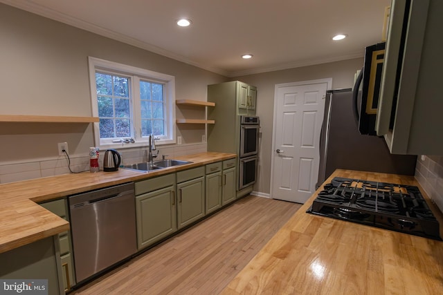 kitchen featuring stainless steel appliances, sink, butcher block counters, light hardwood / wood-style floors, and green cabinets