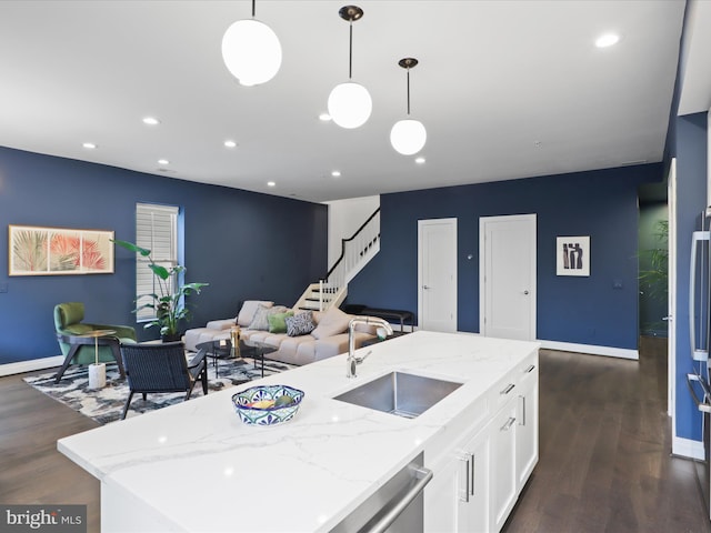 kitchen with a center island with sink, hanging light fixtures, and dark wood-type flooring