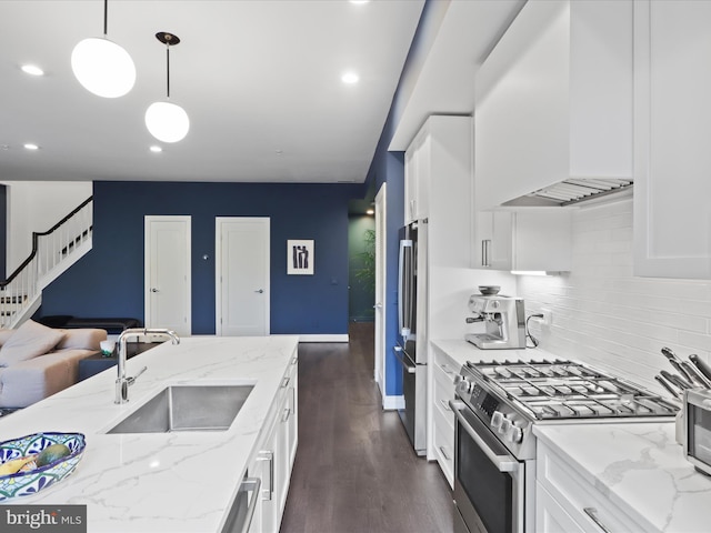 kitchen with dark wood-type flooring, light stone counters, stainless steel appliances, decorative light fixtures, and sink