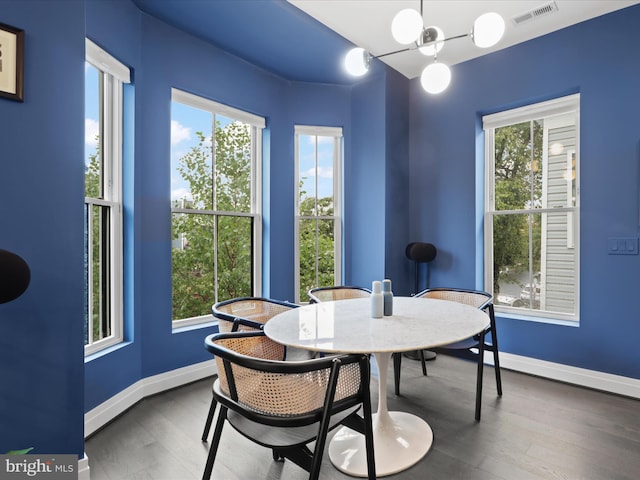 dining area featuring a wealth of natural light, a chandelier, and dark hardwood / wood-style flooring