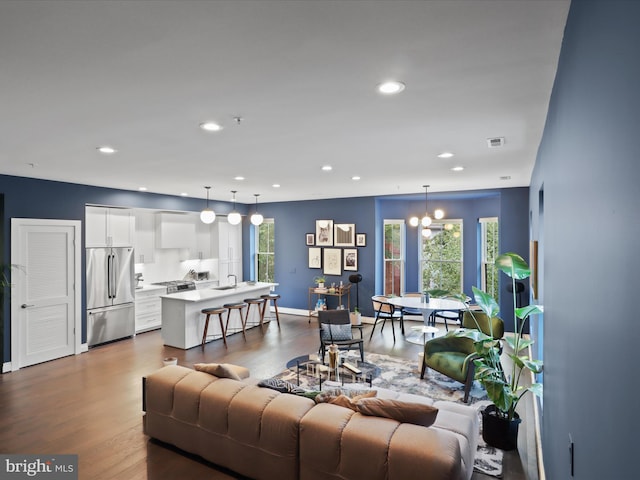 living room with an inviting chandelier, sink, and hardwood / wood-style flooring