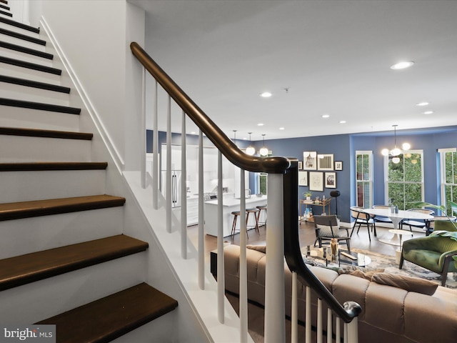 stairway featuring hardwood / wood-style floors and a notable chandelier