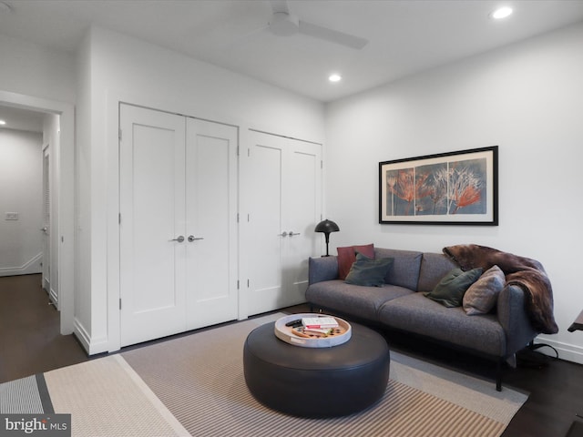 living room featuring dark wood-type flooring and ceiling fan