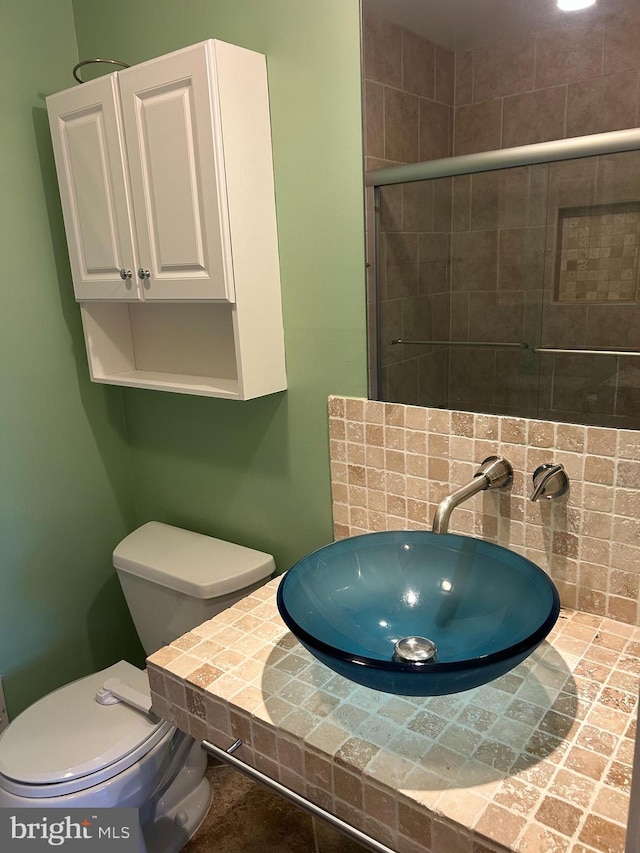 bathroom featuring a tile shower, a sink, and toilet