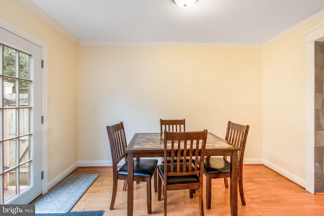 dining space featuring light wood-type flooring, crown molding, and baseboards