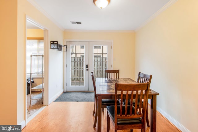 dining room with visible vents, baseboards, ornamental molding, french doors, and light wood-type flooring