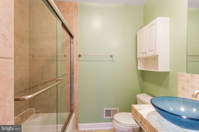 bathroom featuring enclosed tub / shower combo, toilet, vanity, visible vents, and baseboards