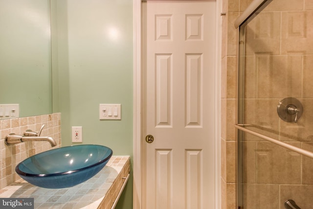 full bath featuring tiled shower, vanity, and tasteful backsplash