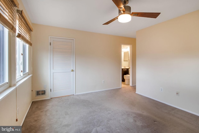 unfurnished bedroom with carpet, connected bathroom, visible vents, and baseboards