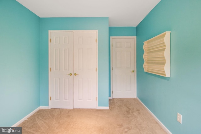 unfurnished bedroom featuring carpet floors, a closet, and baseboards