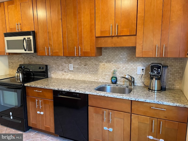 kitchen with black appliances, brown cabinets, and a sink