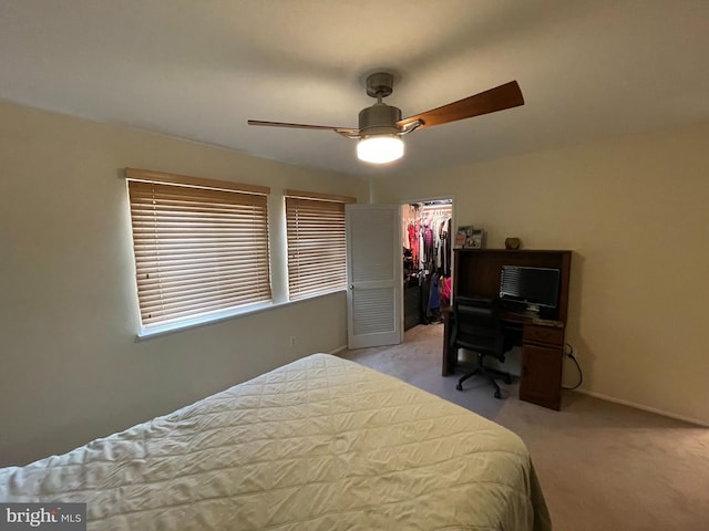 bedroom with light carpet, baseboards, a ceiling fan, a walk in closet, and a closet