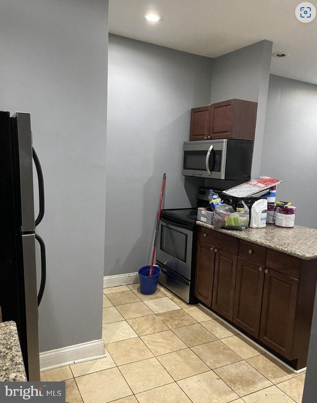 kitchen featuring dark brown cabinets, light tile patterned floors, and stainless steel appliances