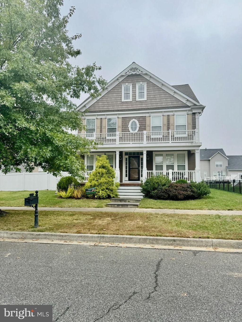 view of front of home with a balcony, a front lawn, and a porch