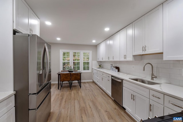 kitchen with sink, white cabinetry, stainless steel appliances, and light wood-type flooring