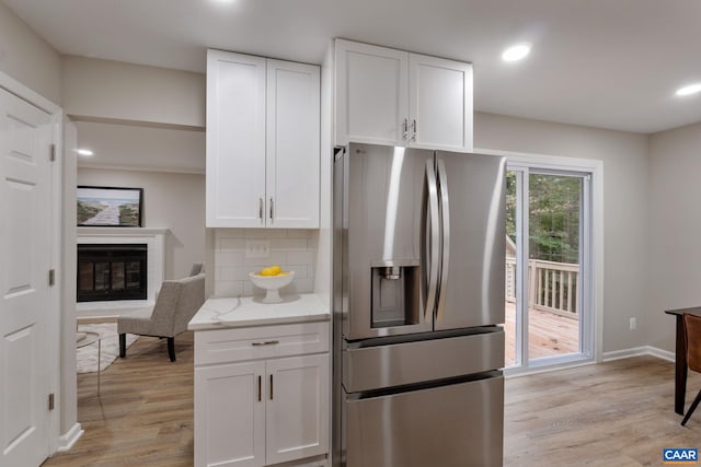 kitchen featuring light stone counters, white cabinetry, stainless steel refrigerator with ice dispenser, and light hardwood / wood-style floors