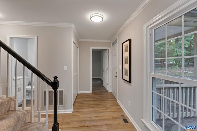 corridor with ornamental molding and light wood-type flooring