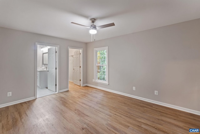 unfurnished bedroom featuring connected bathroom, a closet, light wood-type flooring, and ceiling fan