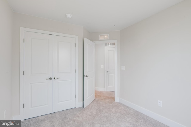 unfurnished bedroom with a closet and light colored carpet