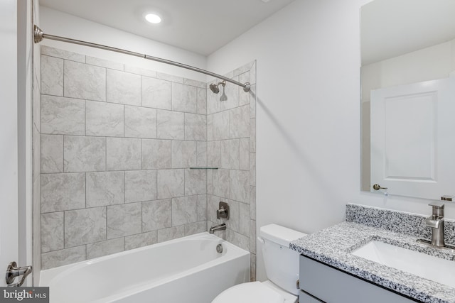 full bathroom featuring tiled shower / bath combo, vanity, and toilet